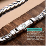 Silver bracelet with 'S925' stamp on a wooden surface, featuring text about silver properties.