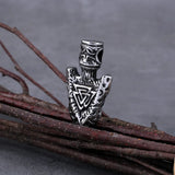 Silver pendant with intricate designs on a branch against a gray background