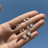 Diamond earrings displayed on a hand with size labels against a blue background
