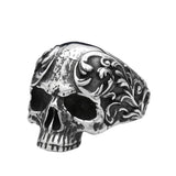 Silver skull ring with intricate designs on a white background