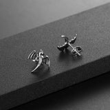 Two Dragon stud earrings on a black textured surface