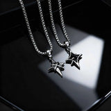 Two silver star-shaped pendants on chains against a dark background