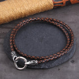 Brown braided leather bracelet with silver clasp on a dark surface