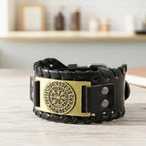 Black leather bracelet with gold emblem on a wooden surface
