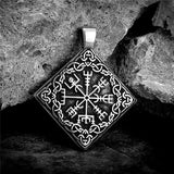 Silver pendant with intricate design on a stone surface