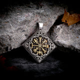 Silver and gold Keyring pendant  with intricate design on a dark stone surface