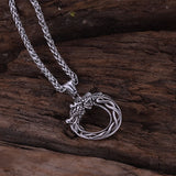 Silver necklace with a dragon pendant on a wooden surface