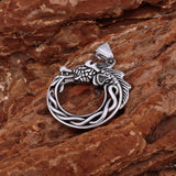 Silver dragon pendant on a textured brown surface