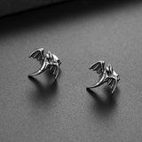 Pair of silver dragon-shaped earrings on a dark surface