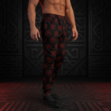 A man wearing black jogger-style pants with a repeating red circular viking symbol pattern, standing against a dark decorative background.