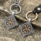 Two keychains with intricate Norse  designs on a stone surface 