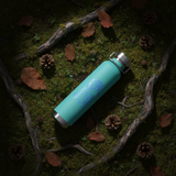 Turquoise lighter with blue design on a mossy surface with leaves and twigs.